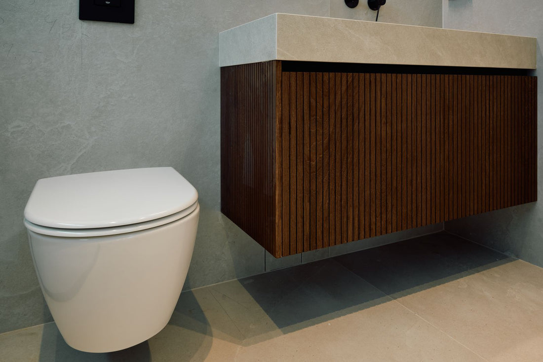 A wall hung white toilet beside a walnut vanity unit in a calm, minimal bathroom