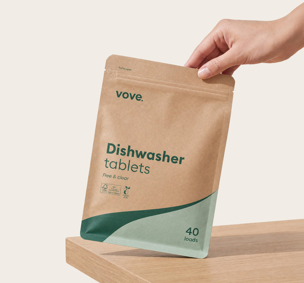 Hand holding the dishwasher tablets pouch on a wooden worktop