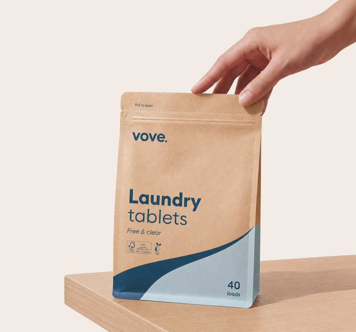 Hand holding the laundry tablets pouch on a wooden worktop