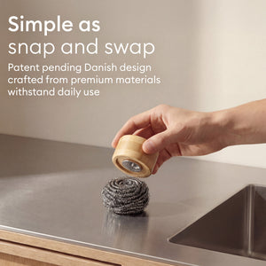 Scrubber Set: hand snapping a fresh pad onto the bamboo holder, patent pending Danish design
