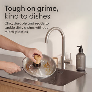 Cleaning Essentials: brush cleaning a pan at the sink, tough on grime and kind to dishes